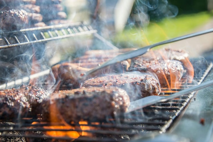 Barbecue tongues and hamburgers on the grill